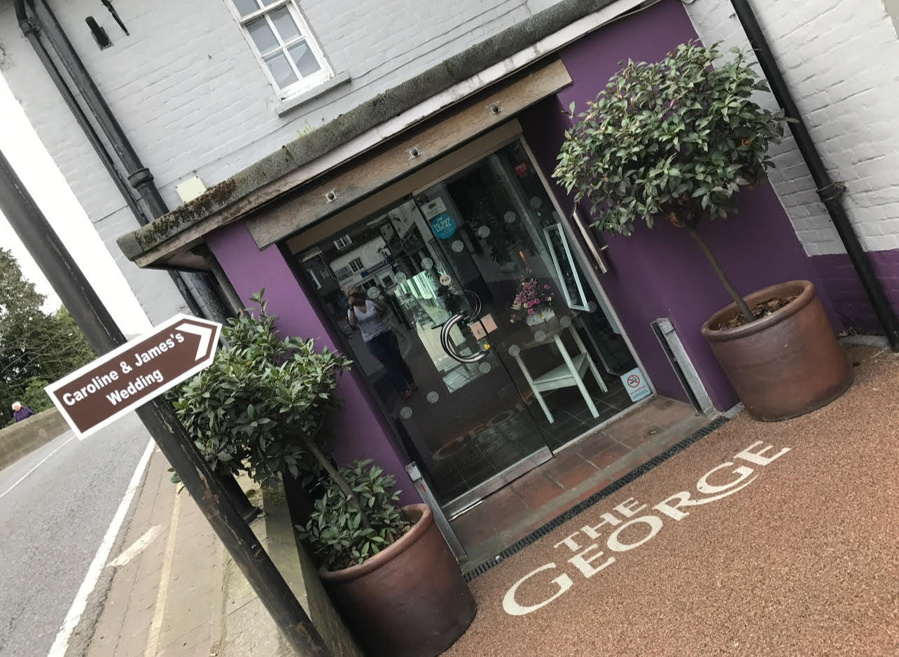 A sign which reads Caroline & James's Wedding pointing to the entrance to The George